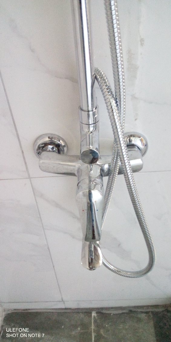 Chrome shower fixture system mounted on a marble-tile wall