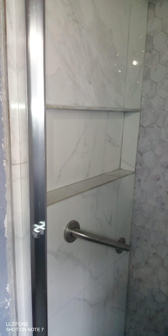 Tiled shower with marble-look tile, recessed niche and mosaic accent