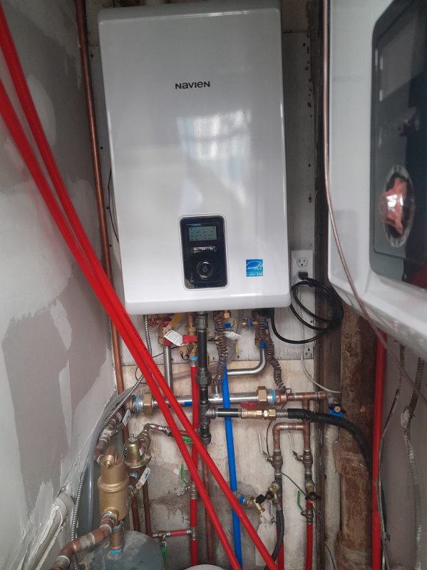 Wall-mounted Navien tankless water heater with copper and PEX piping