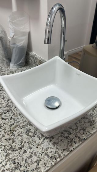 Modern white square vessel sink with a chrome gooseneck faucet on a granite countertop