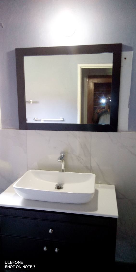 Modern bathroom vanity with white vessel sink, chrome faucet and marble-look tile walls